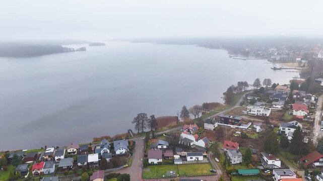 fog washed charzykowy village poland quiet lakeside homes muted autumn gardens mist covered lake fading into horizon wide aerial view drone mavic houses landscape scenery peace 