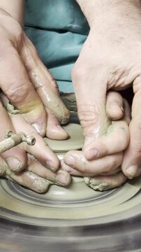 Adult and kid making pottery together. Closeup. Vertical.