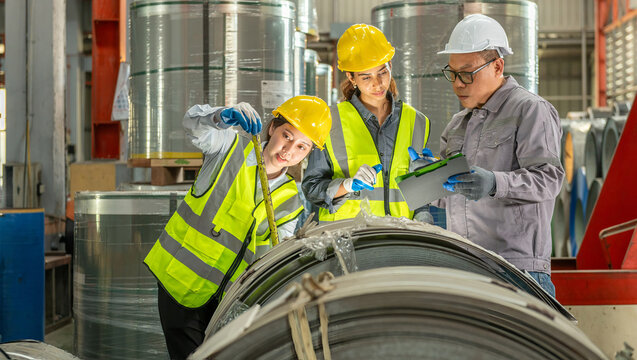 Business professionals inspecting metal coils in industrial warehouse factory plant wea safety gear and high visibility vests for quality assurance and safety