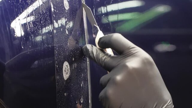 A car wrapping specialist applies a polyurethane film to the car. Selective focus. PPF protective film against chips and scratches. Anti-gravity protection. PFF is installed. Car wrapping close-up.