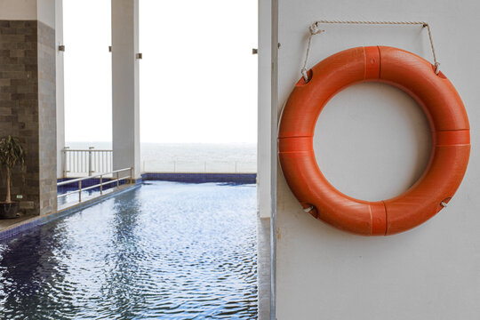 Bright Orange Rescue Lifebuoy Mounted on a Wall by a Swimming Pool
