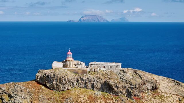 Farol Sao Lourenco lighthouse on remote cliff edge with Atlantic Ocean horizon, Madeira Island aerial shot