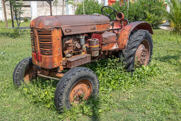 Obraz premium An old tractor. Retro technology. Vintage agricultural equipment. An old rusty tractor with big wheels. Harvesting equipment.