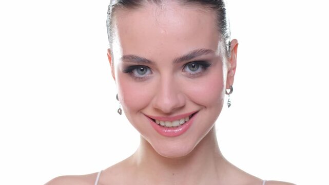 Young woman smiling then winking and blowing kiss to camera, beauty portrait, studio shot on white background