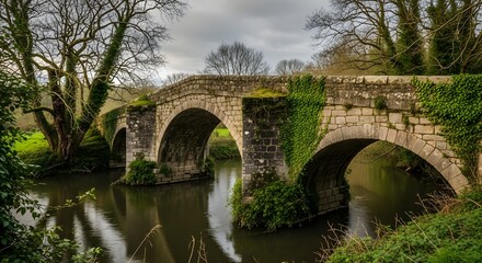 Fototapeta premium A historic stone bridge spans a serene river surrounded by lush greenery