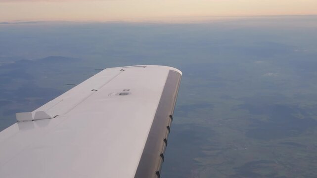cruising airplane clean wingtop above layered clouds rolling terrain white wing reflecting soft daylight aircraft glides high polish reveals smooth view embraer e190 poland 