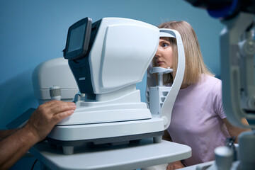 Young woman getting eye exam at ophthalmology clinic with optometrist