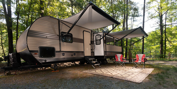Shady spot in a forested campsite with awnings out on a travel trailer