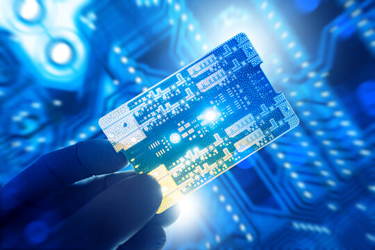 Electronics manufacturing, Microtechnology. Technician in gloves holds printed circuit board, inspecting components for quality control, testing, assembly and semiconductor production.