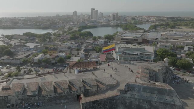 rone flying around main flag of castillo san felipe overlooking the sea n the main entrance then desending to the estatue infront during the day