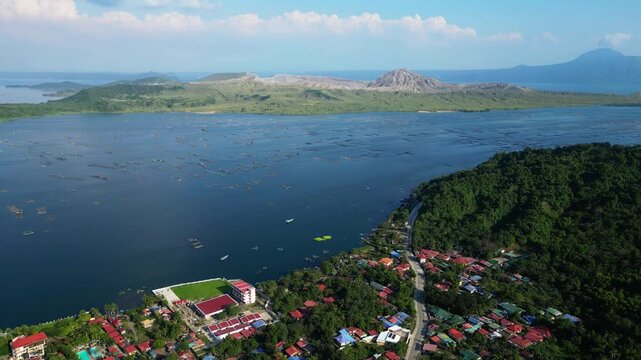 High-altitude drone capturing Taal Volcano, Binitiang malaki western Point of Taal Volcano, mountains, and square ocean fishponds and tiny house in Agoncillo Laurel, Batangas, Philippines.