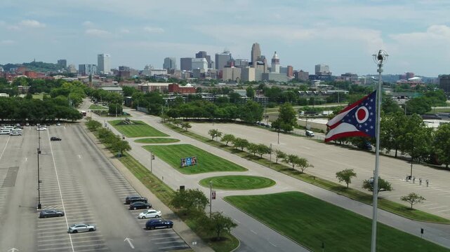 Cincinnati, Ohio skyline in the distance with Ohio state flag in the foreground with drone video moving forward.