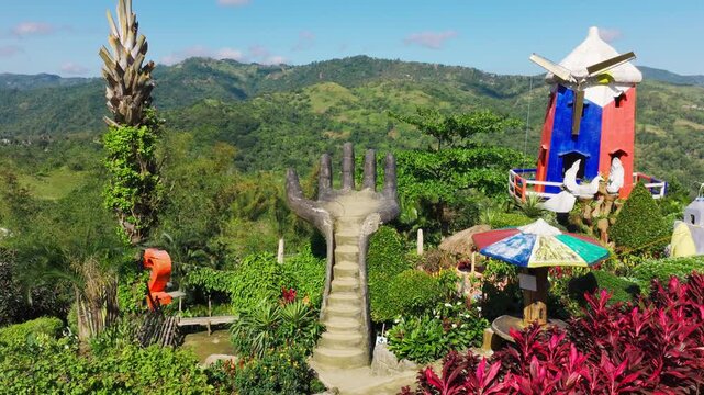 Drone glides forward to concrete hand staircase, windmill Cebu City Philippines