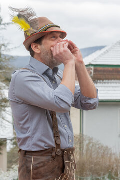 Adult man in Tyrolean hat performing yodel in Alpine village Austria