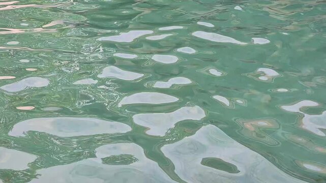 Calm swimming pool water surface with gentle ripples and sunlight reflections, relaxing blue abstract background