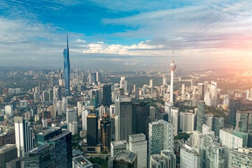 Fototapeta premium Expansive view of Kuala Lumpur, Malaysia, at sunrise. The city's many modern skyscrapers rise under a blue sky, featuring the iconic Kuala Lumpur Tower