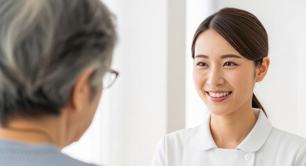 Fototapeta premium A young woman smiling and talking to an elderly person.