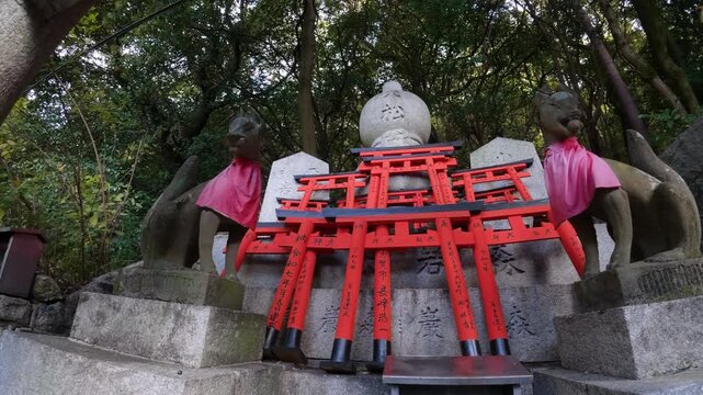 Small red Torii Gate offerings and stone Kitsune fox statues at Fushimi İnari-taisha in Kyoto