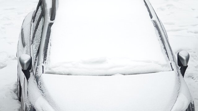 Ośnieżony samoch&oacute;d na parkingu w okresie zimowym