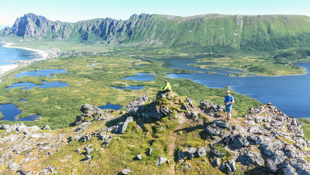 aerial, bird view 2 caucasian hikers on Laupen mountain during summer, village bleik, beach, mountains in background. Bleikmorenen nature reserve Vester&aring;len, vesteralen islands Beautiful hiking destin