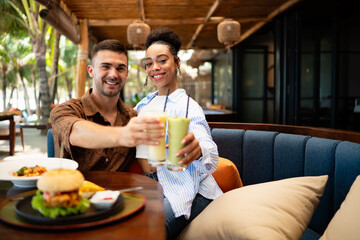 Young couple sharing dining experience at tropical restaurant, engaging with their online followers