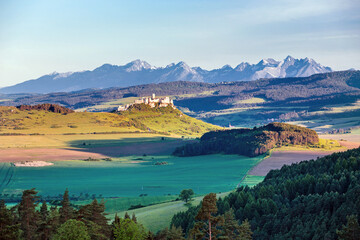 Naklejka premium Spiš Castle (Spišský hrad) in Slovakia, a historic stone fortress perched on a hilltop, with panoramic views of the surrounding mountains. Dramatic sky, vibrant colors, and natural light highlight the