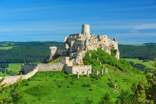 Spi&scaron; Castle (Spi&scaron;sk&yacute; hrad) in Slovakia, a historic stone fortress perched on a hilltop, with panoramic views of the surrounding mountains. Dramatic sky, vibrant colors, and natural light highlight the