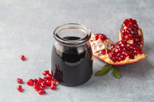Glass bottle of pomegranate sour sauce with fresh ripe whole and split pomegranate fruit (Turkish name; nar eksisi)