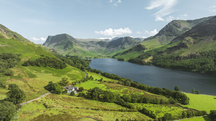 Obraz premium Serene lake nestled between lush green mountains under a clear blue sky
