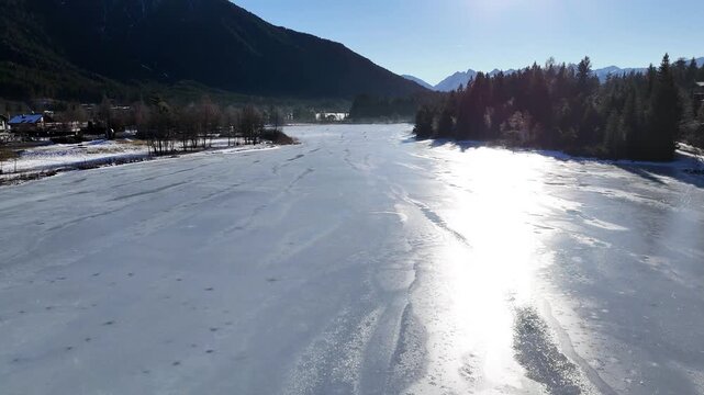 crisp alpine village seefeld chalet style houses pine trees lining partially frozen lake snow patched walking path forested mountain slopes under clear blue rising view tirol austria 
