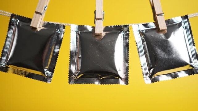 Three condom packages hanging on a rope with clothespins