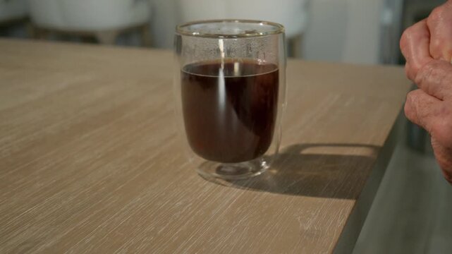 older male adds sugar to his early morning drink of choice, coffee, a stimulant consumed by many seniors