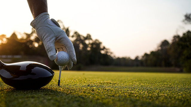Golfer Placing Tee and Ball on Golf Course During Golden Hour Light