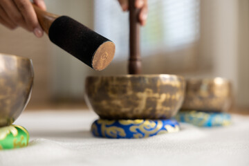 Peaceful unrecognizable person playing Tibetan singing bowl with wooden mallet for sound therapy healing session promoting spiritual relaxation wellness and calm mindful zen atmosphere indoors © 220 Selfmade studio