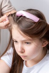 Fototapeta premium Mom's hands twist curlers for daughter in white T-shirt at home on a light background in front of the mirror