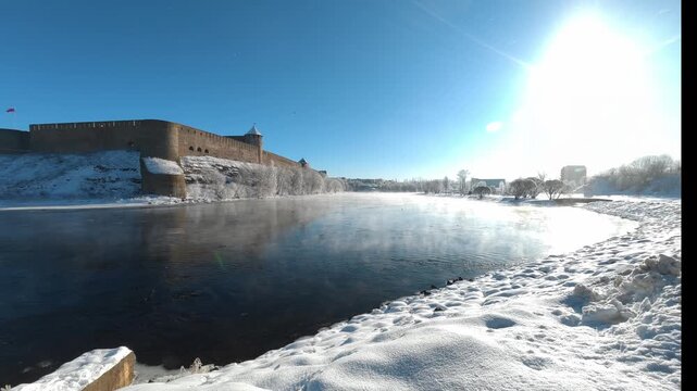 Narva, Estonia &ndash; February 2026: Morning mist rising over the Narva River near the historic Ivanogorod Fortress on the Russia&ndash;Estonia border during winter sunrise.