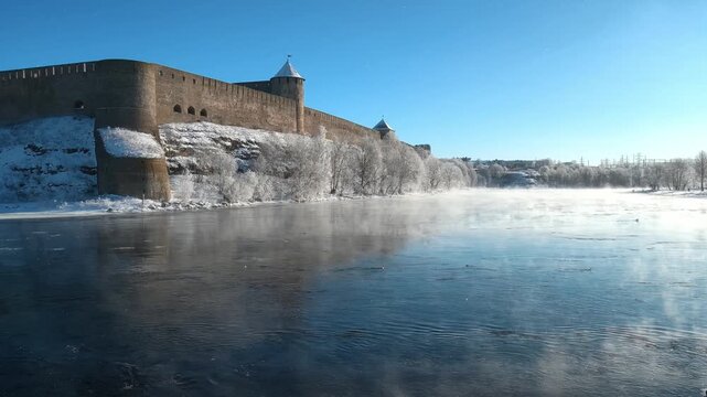 Narva, Estonia &ndash; February 2026: Morning mist rising over the Narva River near the historic Ivanogorod Fortress on the Russia&ndash;Estonia border during winter sunrise.