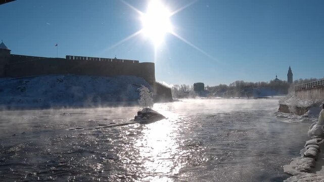 Narva, Estonia &ndash; February 2026: Morning mist rising over the Narva River near the historic Ivanogorod Fortress on the Russia&ndash;Estonia border during winter sunrise.