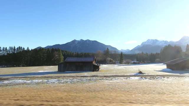 rustic wooden hut sits isolated frost covered meadow framed by dense evergreen forests hazy blue silhouette prominent mountain peak seefeld tirol austria barn frosty alps landscape 