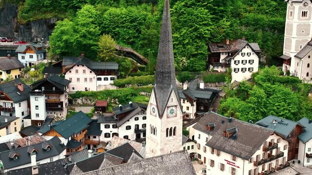 Aerial drone footage of Hallstatt, Austria, showing the picturesque alpine village, lake shoreline, historic buildings, and surrounding mountains.