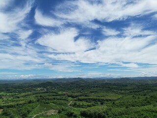 Obraz premium Scenic view of lush green mountain range under beautiful blue sky and white clouds