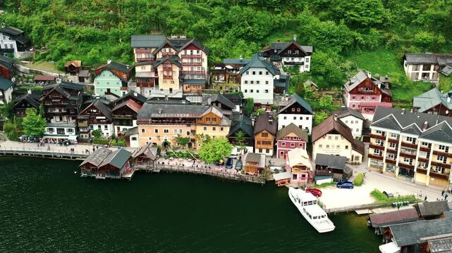 Aerial drone footage of Hallstatt, Austria, showing the picturesque alpine village, lake shoreline, historic buildings, and surrounding mountains.