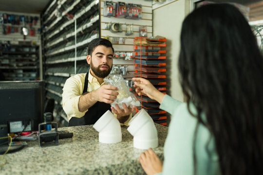 Hardware store clerk assisting a female customer with plumbing supplies at the payment counter