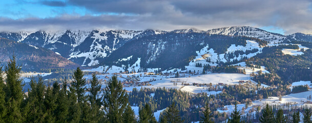 Winter landscape at the foot of the Nagelfluhkette with the snow-covered Hochgrat peak above Steibis near Oberstaufen in the Allg&auml;u region of Bavaria, Germany, under soft afternoon light.