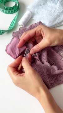 A woman carefully unpicks a seam on lace fabric with ripper.