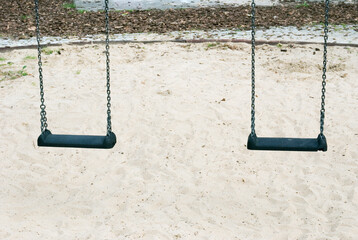 pair of children swings over the sand 