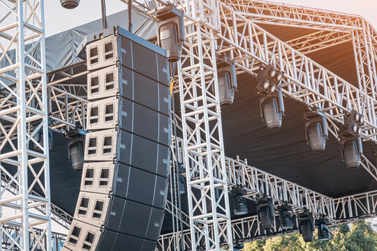 Professional audio line array speakers and moving head light fixtures hanging on a metal truss structure for an outdoor event or concert