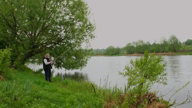 Professional fisherman casting a spinning rod into the lake.