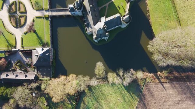 perspective geometric layout castle laarne stone keep's grey rooftops inner grass courtyard adjacent symmetrical hedge garden to overhead drone of belgium flanders flemish 