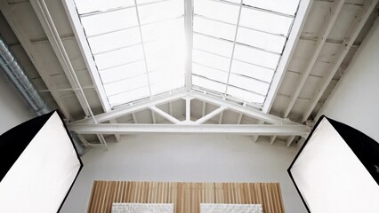 Obraz premium Minimal photo studio interior with skylight roof and white beams, soft daylight for professional shoots and content creation, clean modern workspace mood